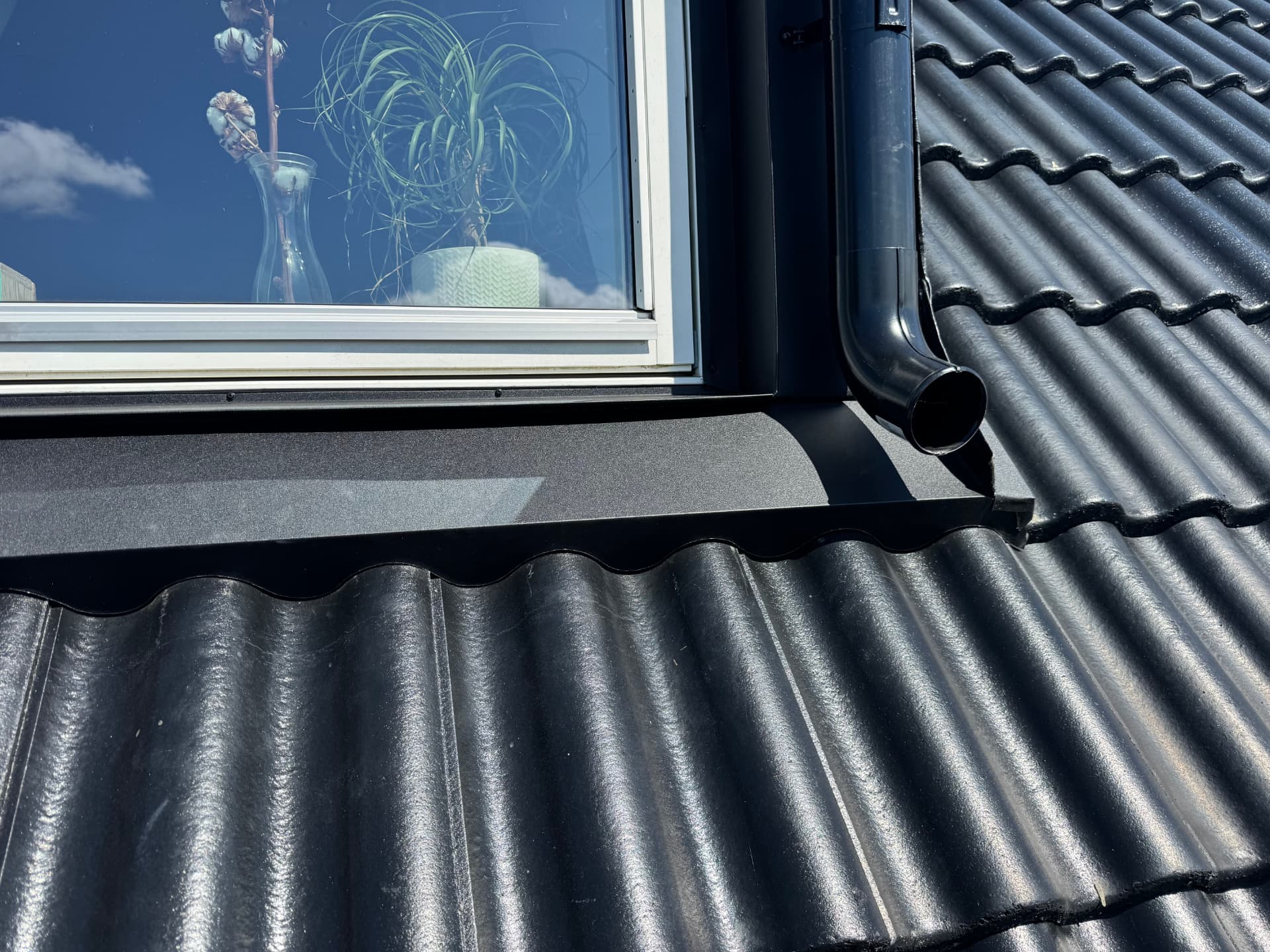 Detalj av svart plåttak med fönsterbleck och stuprör